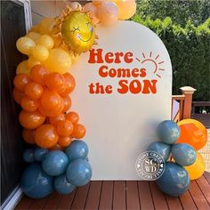 there is a sign that says here comes the son and balloons are in front of it