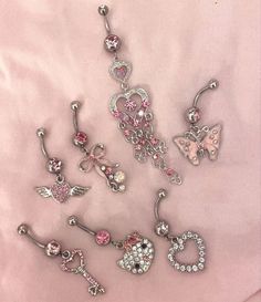 several different types of belly piercings on a pink sheet with butterfly, heart and flower designs