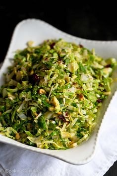 a white plate topped with shaved brussels sprouts and cranberry bits on top