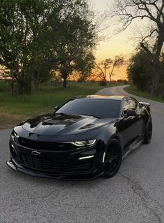 a black chevrolet camaro is parked on the road