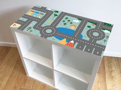 a children's table with cars and roads painted on the top, sitting in front of a white wall