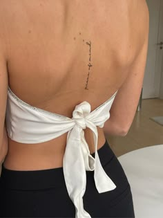 the back of a woman's white top with a tattoo on her lower back