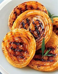 grilled onion rings on a white plate with rosemary garnish and seasoning