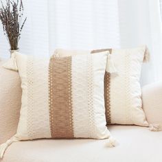 three pillows with tassels are sitting on a couch