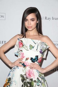 a woman in a floral dress poses for the camera with her hands on her hips