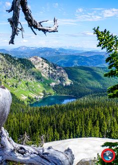 a view of a lake and mountains from the top of a mountain with a red circle in the foreground