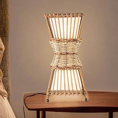 a lamp made out of bamboo sticks sitting on top of a table next to a bed