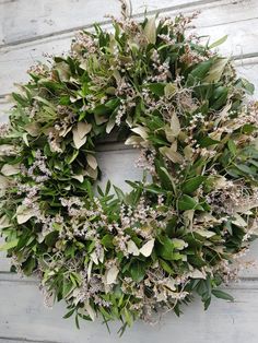 a wreath is hanging on the side of a building with leaves and flowers around it