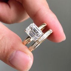 a person holding an engagement and wedding ring set in their left hand, with the diamond on each side