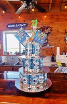 a stack of beer cans sitting on top of a wooden counter next to a ceiling fan