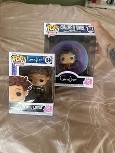 two pop vinyls are sitting on a bed with the covers pulled down and one is holding an object in it's hand