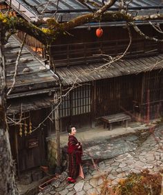 a woman standing in front of a building with an orange ball hanging from it's roof