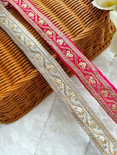 two different colored belts sitting next to each other on top of a white cloth covered basket