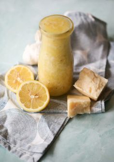 a glass jar filled with yellow liquid next to sliced lemons on a cloth and napkin