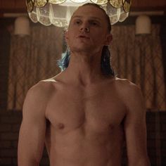 a shirtless man with blue hair standing in front of a chandelier and looking at the camera