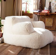 a white chair sitting on top of a wooden floor in front of a christmas tree