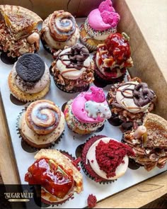 a box filled with lots of different flavored cupcakes on top of a table