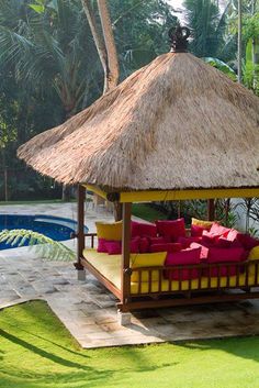 a gazebo sitting next to a swimming pool in the middle of a lush green yard