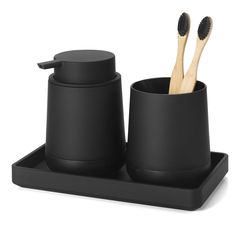 two toothbrushes in black cups on a tray with wooden spoons and brush holders