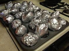 muffin tins wrapped in aluminum foil sitting on top of an oven burner