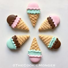 six decorated ice cream cones are arranged in a circle on a white surface with blue, pink and brown icing