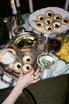 a table filled with food and drinks on top of a white marble countertop next to candles