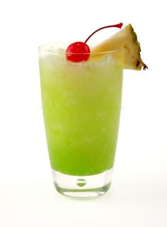 a green drink with a pineapple garnish and a cherry on the top