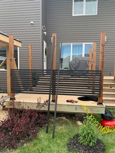 a wooden deck in front of a house with plants and tools on the ground next to it