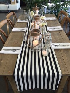 a long table with candles and vases on it is set for an outdoor dinner