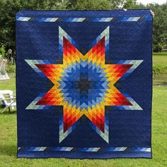 a blue quilt with an orange, yellow and red star in the center on grass