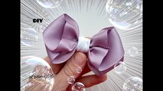 a hand holding a purple bow with bubbles around it