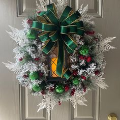 a christmas wreath on the front door with a lit candle in it and evergreens