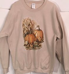 Autumn Pumpkin & Corn Husks T Shirt, (Sweatshirt,  Hoodie Available On Request) #794a For Sweatshirts and Hoodies please contact me to request a custom order. Youth Sizes available Design will be printed on the front of the garment unless requested otherwise. The exception to this is hoodies where zippers and pockets may obstruct the printing space. 5XL NOT available in LONG SLEEVE LAVENDER & GREEN  (Please order short sleeve style or a different color)   6XL available in short sleeve only and  is NOT available in LAVENDER or GREEN Long sleeve colors may vary from pictured depending on availability from the garment mills.   COLOR: Fabric colors can affect the final print colors. This image shows the design on white. Computer monitors can depict colors slightly differently as well.  Design Hooded T-shirt For Fall Streetwear, Cotton Hooded T-shirt For Fall, Graphic Print Hoodie Sweats For Fall, Hooded T-shirt For Streetwear In Fall, Casual Fleece T-shirt For Fall, Fall Fleece Sweatshirt With Screen Print, Hooded Cotton T-shirt For Fall, Fall Hooded Graphic Print T-shirt, Screen Print Hoodie With Relaxed Fit For Fall