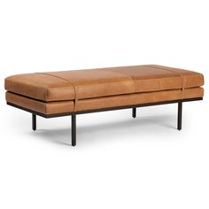 a brown leather bench sitting on top of a metal frame legs and footrests