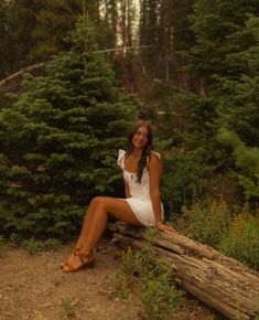 a woman sitting on a log in the woods