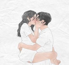 two people kissing each other while sitting on top of a sheet of paper in front of a white wall