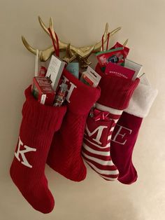 three christmas stockings hanging on the wall with reindeer antlers and other holiday items in them