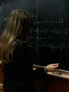 a woman standing in front of a blackboard with writing on it