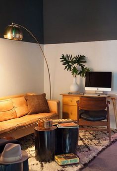 a living room filled with furniture and a computer on top of a wooden desk next to a lamp