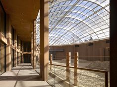 the inside of an indoor building with glass roof and wooden railings on both sides