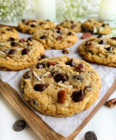 chocolate chip cookies with almonds and coconut on a wooden cutting board next to candles