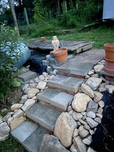 there are many potted plants sitting on the steps in the yard that is made out of rocks