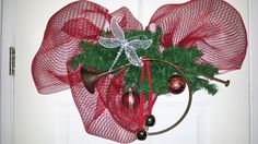 a red mesh wreath with bells and ornaments hanging from it's front door frame