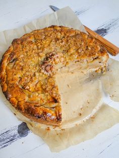 a pie with one slice missing from it on top of parchment paper next to a knife