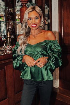 This 'Genuine Reaction Babydoll Top' in hunter green is stunning! Features a lightweight satin material, a wide smocked neckline, long loose sleeves with ruffled elasticized seams, and feminine stitching in the front. The half back smocked design gives it a flattering silhouette that falls into a waist-length hemline.                                   Measurements S :  Bust 28", Hip 32", Length 19", Sleeve Length 21", Waist 26".  M :  Bust 30", Hip 34", Length 20", Sleeve Length 22", Waist 28". Green Satin Party Top, Fall Satin Top With Ruffles, Green Ruffled Tops For Winter, Fall Satin Ruffle Tops, Fall Satin Ruffled Tops, Green Ruffled Winter Tops, Winter Green Ruffled Tops, Loose Sleeves, Model Fits