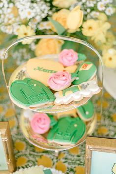 some cookies are in a glass bowl on a table with flowers and other decorations around it