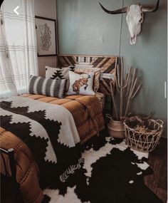 a bed room with a neatly made bed and a cow skull mounted on the wall