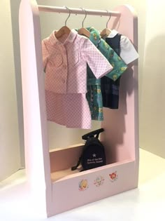 a doll's closet with clothes hanging on the rack and an ironing board