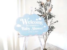 a welcome sign sitting on top of a wooden easel next to a small tree