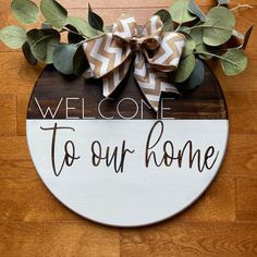 a welcome sign is hanging on the wall next to a wood floor with green leaves